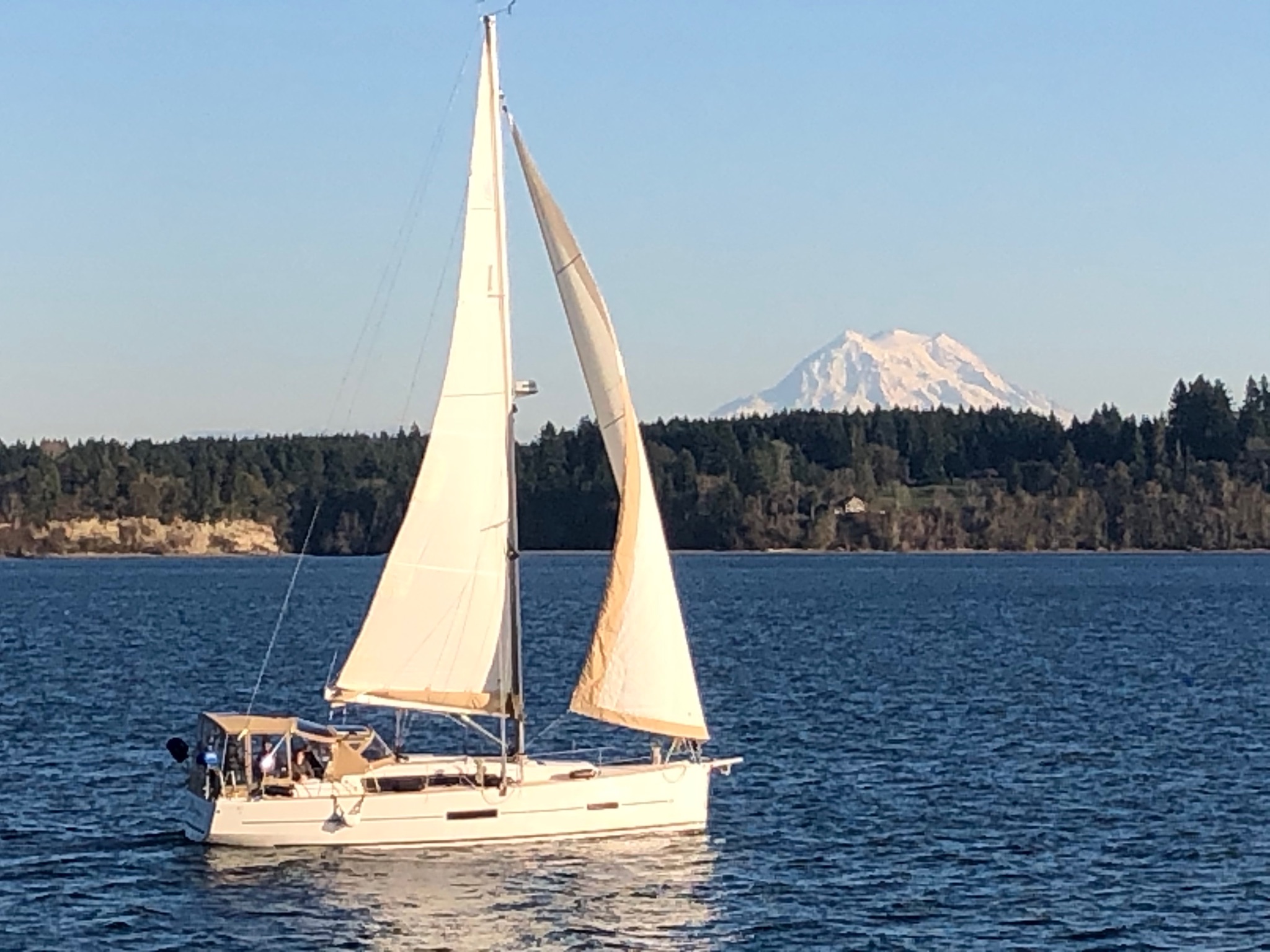 A sailboat underway with Mount Rainier in the distance.