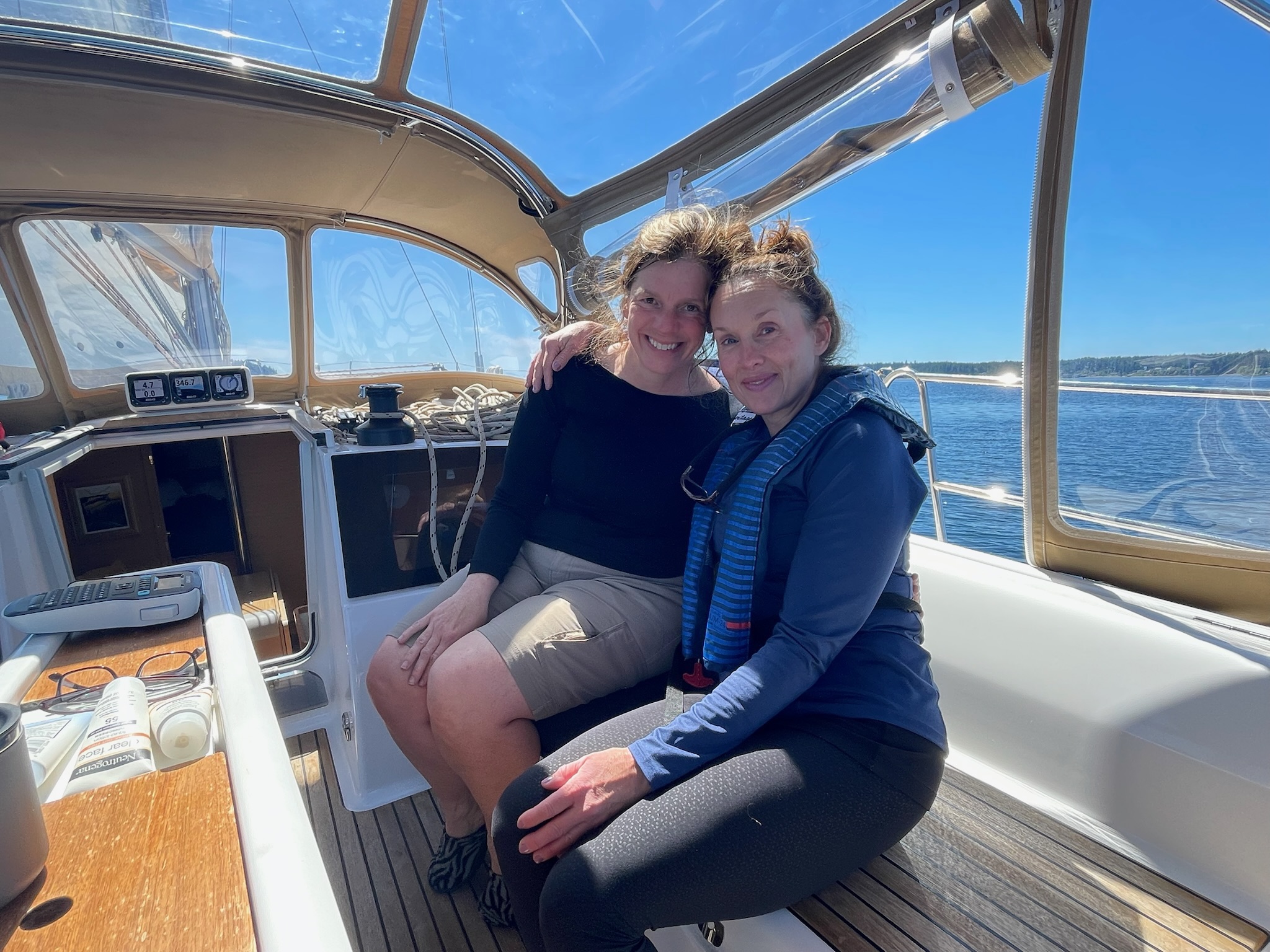 Two guests sitting in the cockpit on a sunny sailing day.