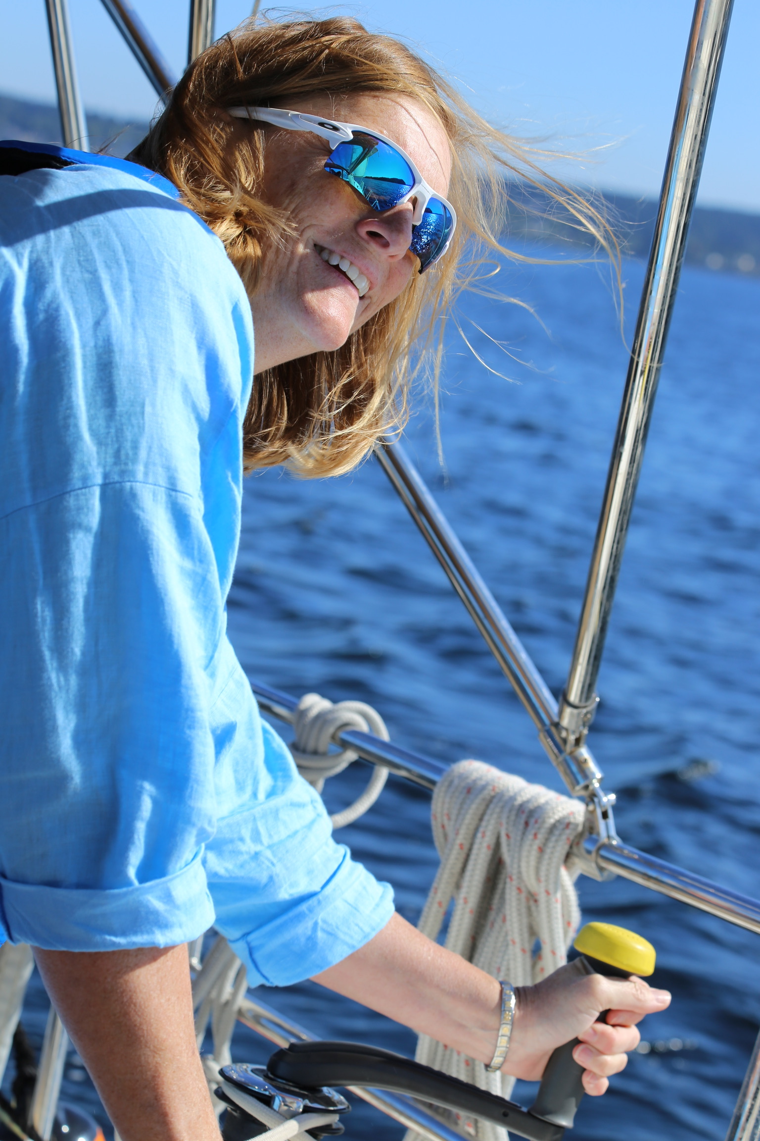A sailor smiling while trimming a line.