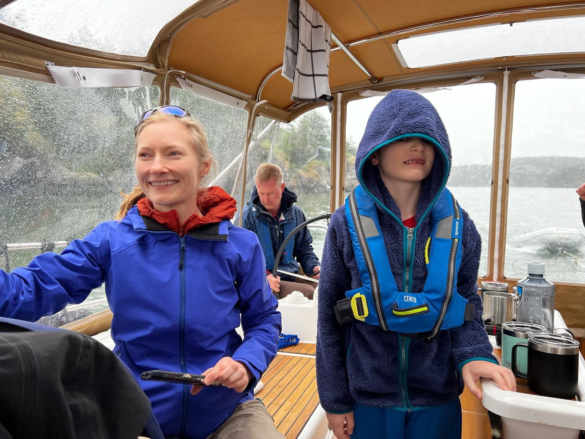 Two young sailors in rain gear aboard the boat.
