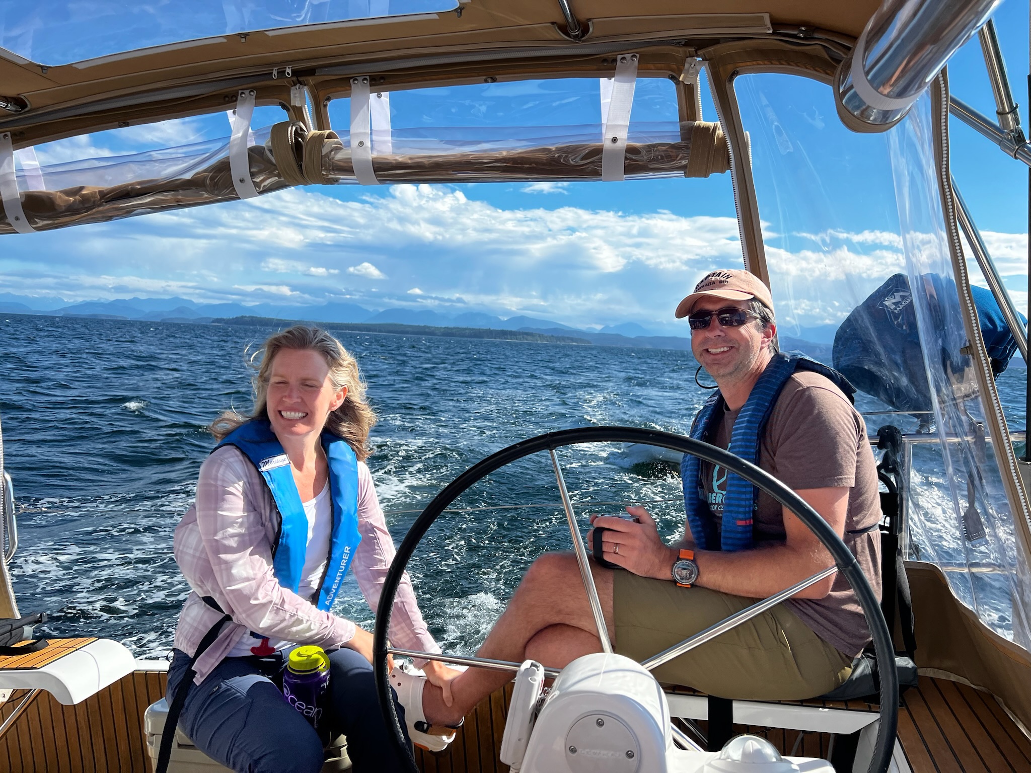 Two sailors sharing the helm underway.