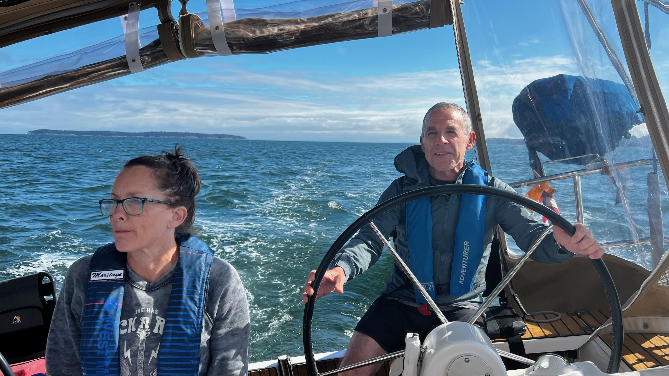 A couple sailing together under a blue sky.