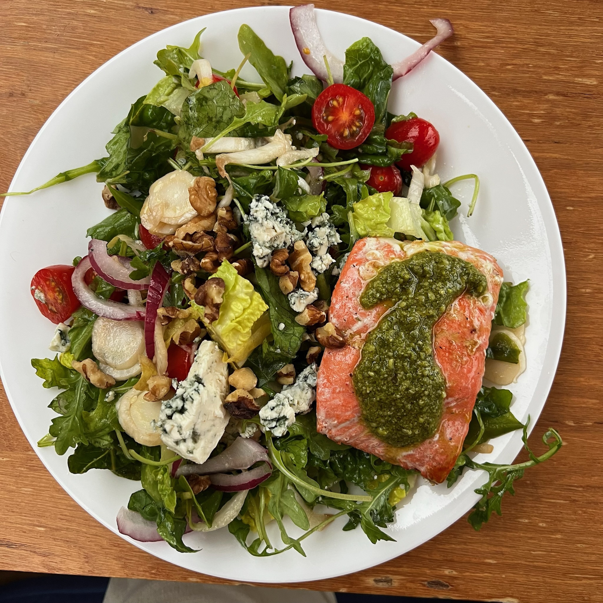 A salmon salad with greens, tomatoes, walnuts, and blue cheese.